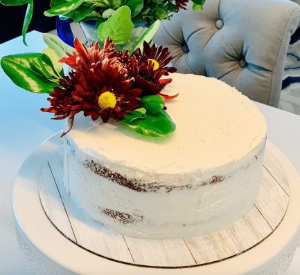 Elegant white cake frosted with half naked vanilla Swiss meringue