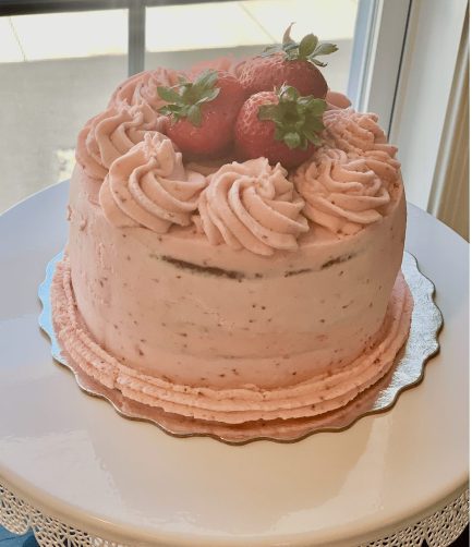 Strawberry Cake topped with fresh strawberries frosted in Strawberry Swiss meringue