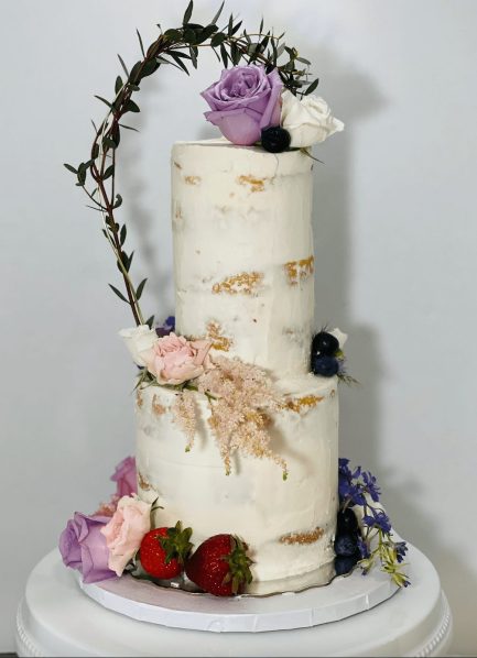 Beautiful two tier semi-naked wedding cake decorated with the brides florals and fresh fruit